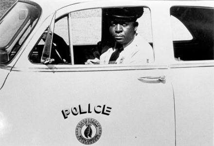 Photo of Clyde Cox in a Police Car.