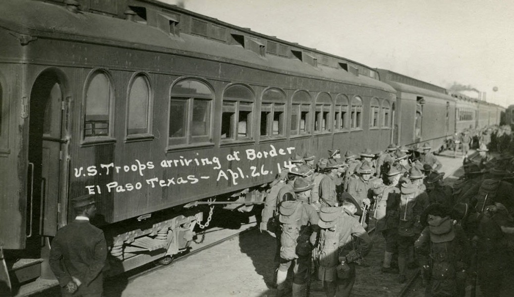 Real photo postcard of soldiers leaving a passenger train car. Text on postcard reads "U.S. troops arriving at Border, El Paso, Texas, April 26, 1914".