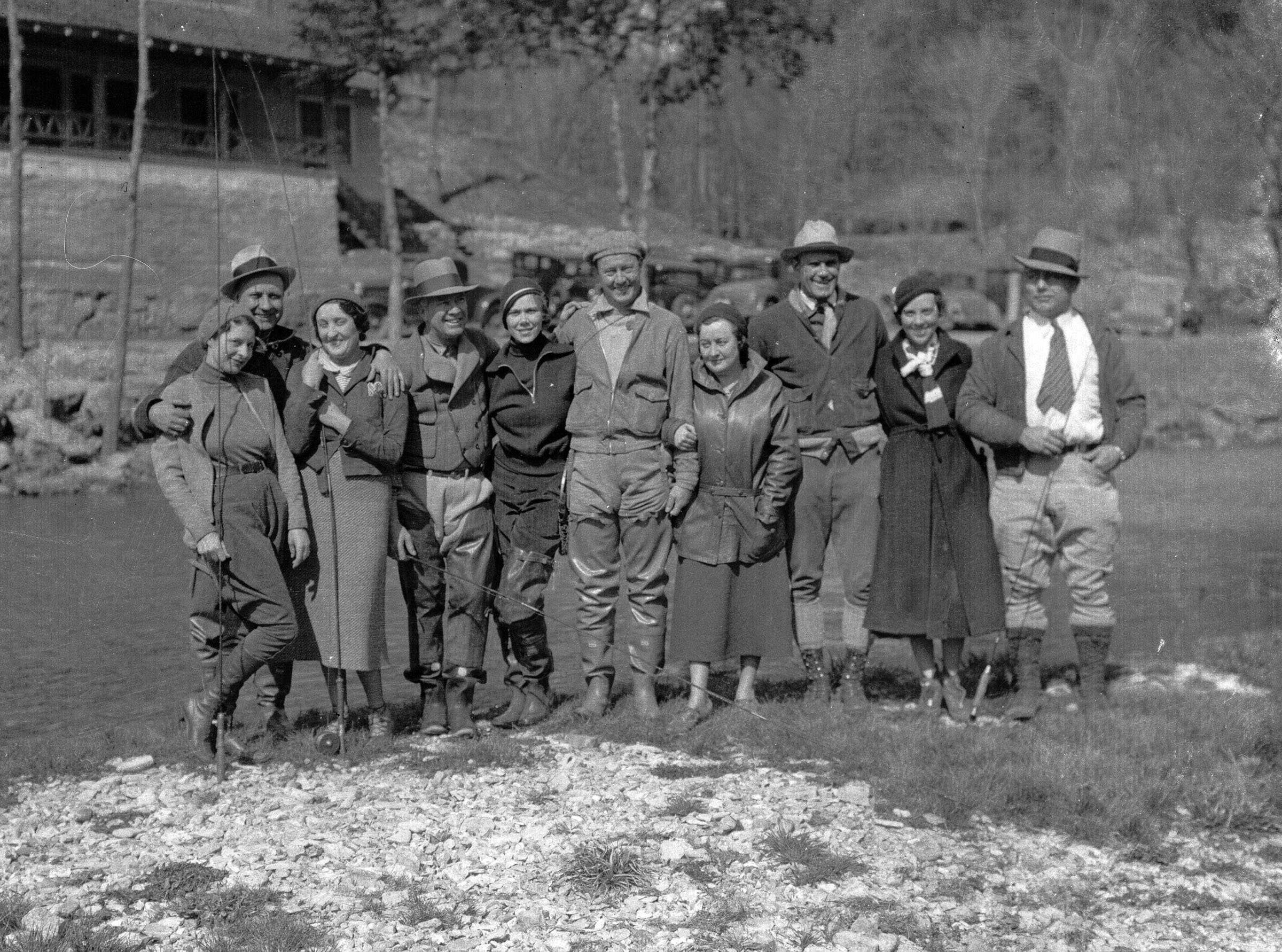 A group of men and women posing outdoors in front of a river.