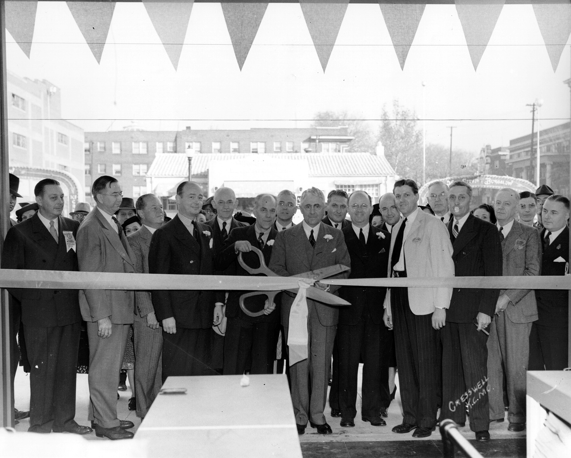 A crown of people standing behind a long ribbon at a dedication ceremony.