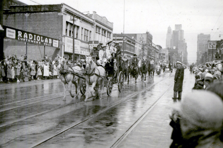 A horse-drawn carriage riding in a parade down a city street