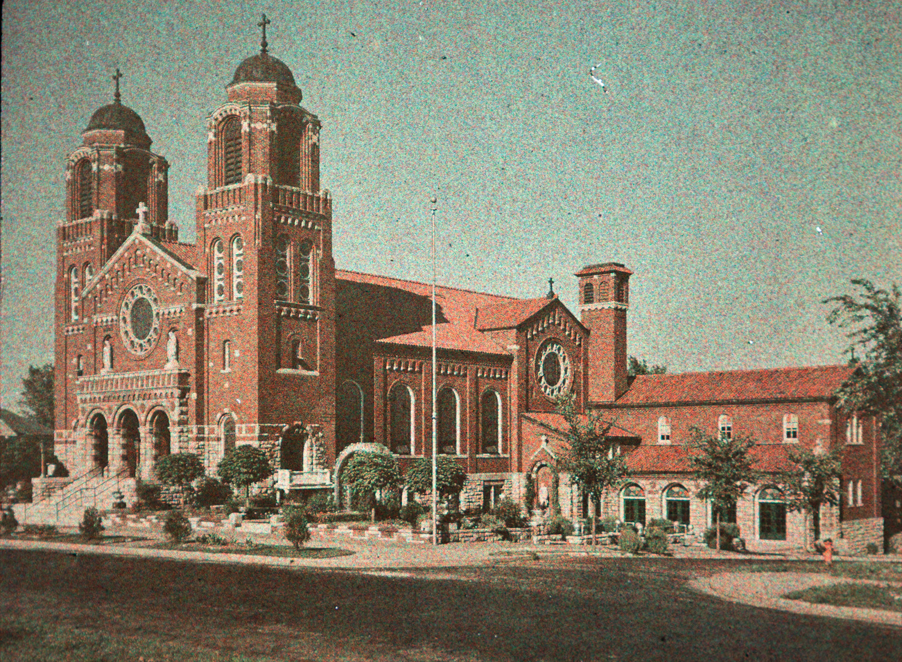 A brick church with two spires adjacent to the entrance