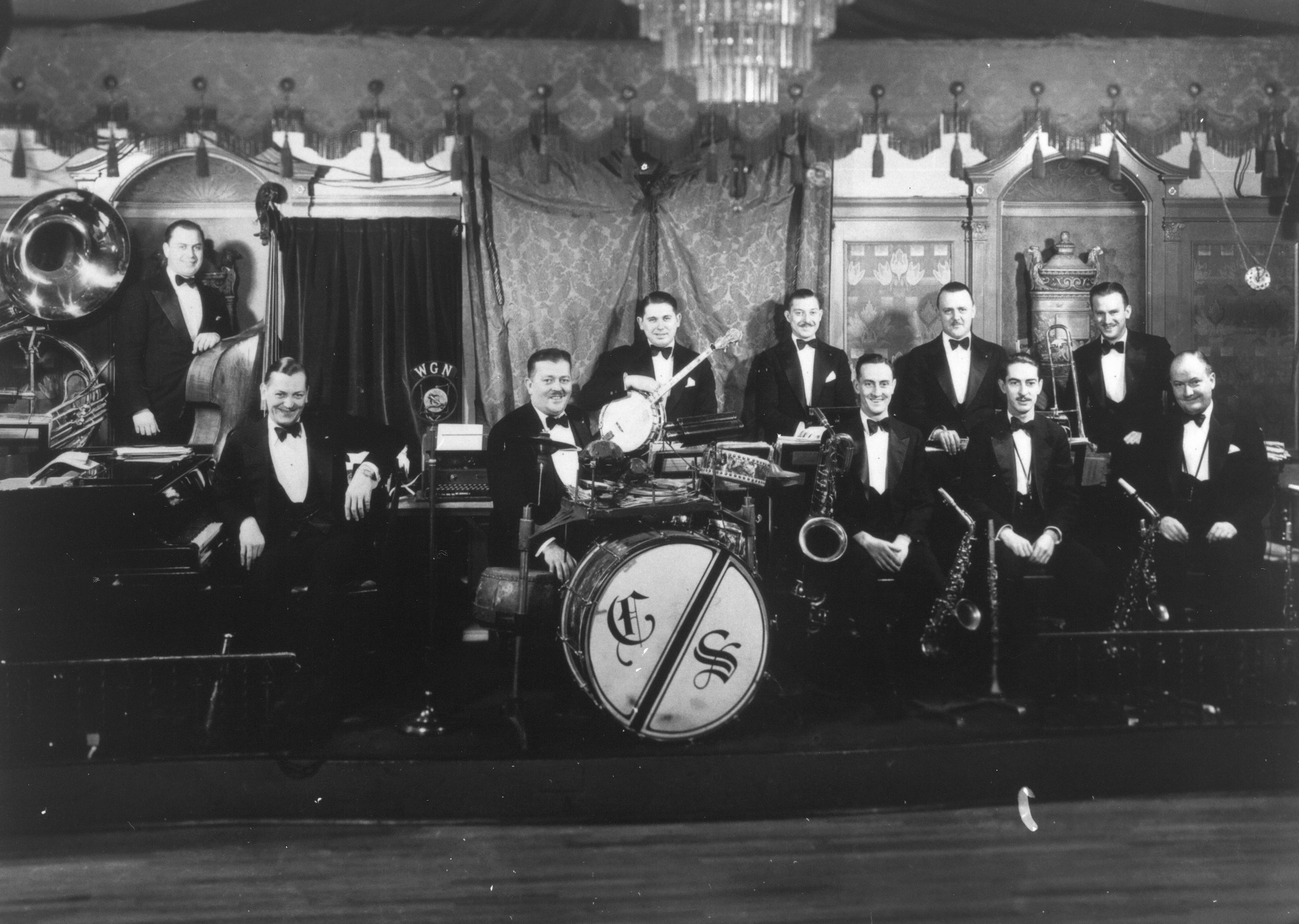 Members of a jazz band posing on stage, holding horns and other instruments