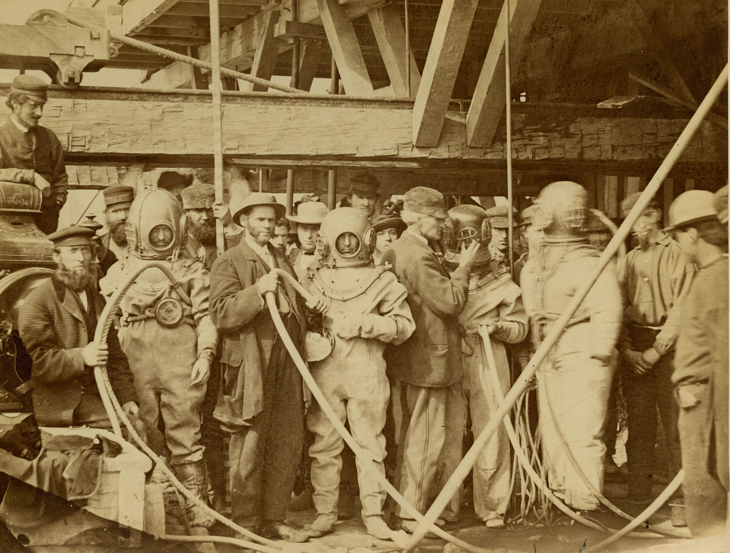 A group of people, some of whom are wearing primitive diving gear.