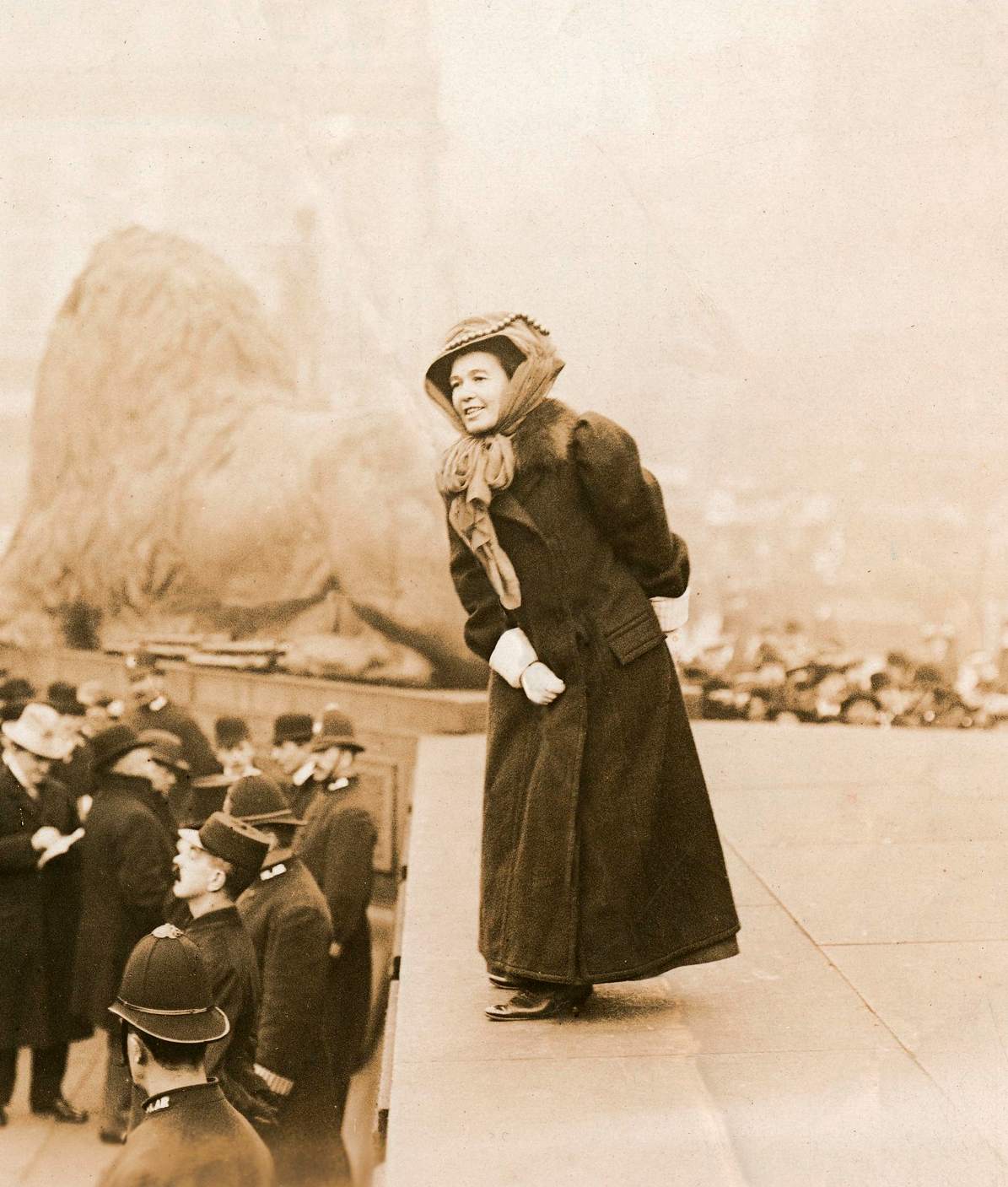 A woman stood on a platform in Trafalgar Square giving a speech to a crowd of people.