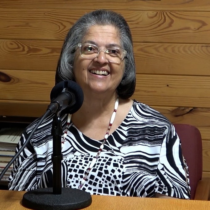 American Indian woman seated at a table in front of a microphone