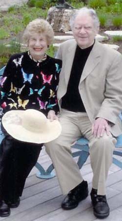 Evelyn and Eric Newman seated on a garden deck, smiling with Eric's arm around Evelyn.