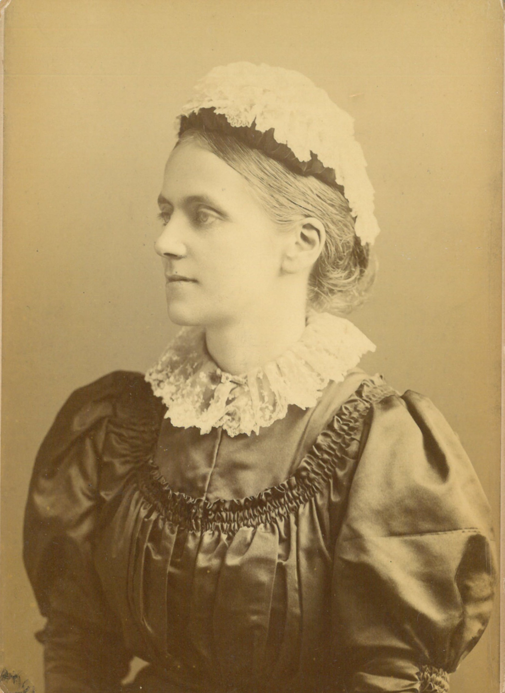 Photographic portrait of Constance Maynard as a young woman with a black dress and white cap.
