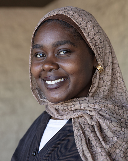 A color headshot potrait of a East African, Black woman wearing a headscarf.