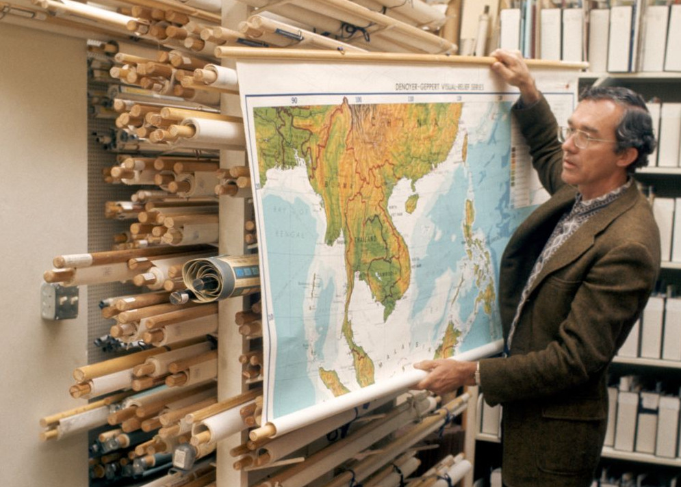 Man in glasses holding up a map in the McHenry Library