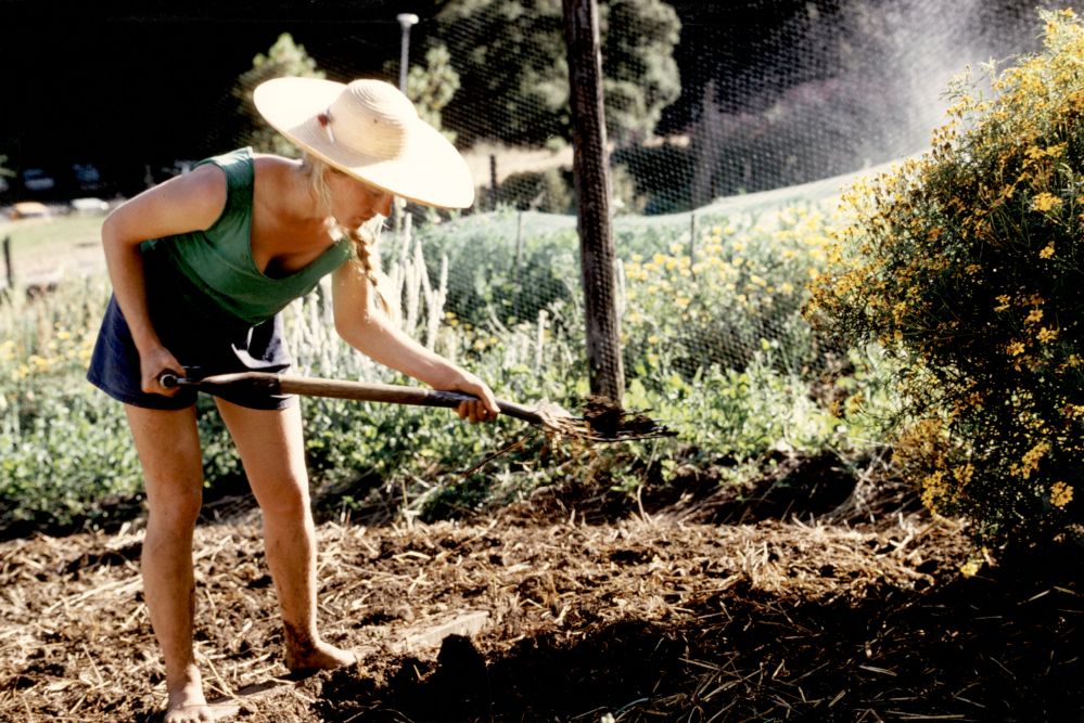 woman in a straw hat gardening out at the USCS Farm.