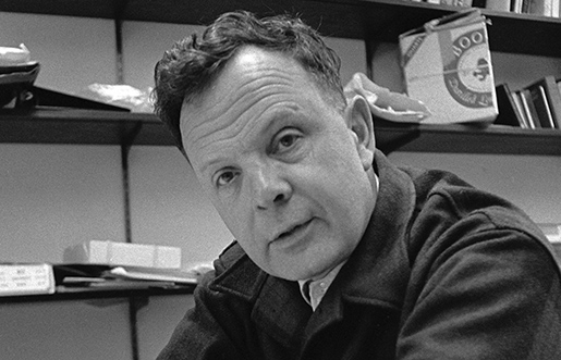 Black & White portrait of Norman O. Brown sitting with his arms crossed at a table.