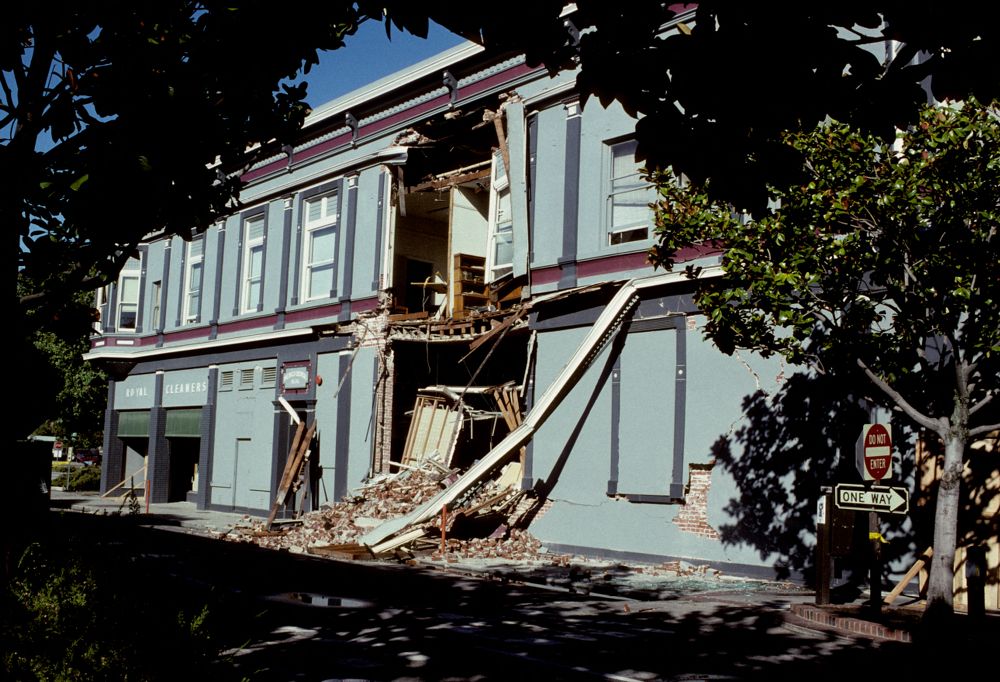 Outside of a building, blue, with earthquake damage to the front doorway. 