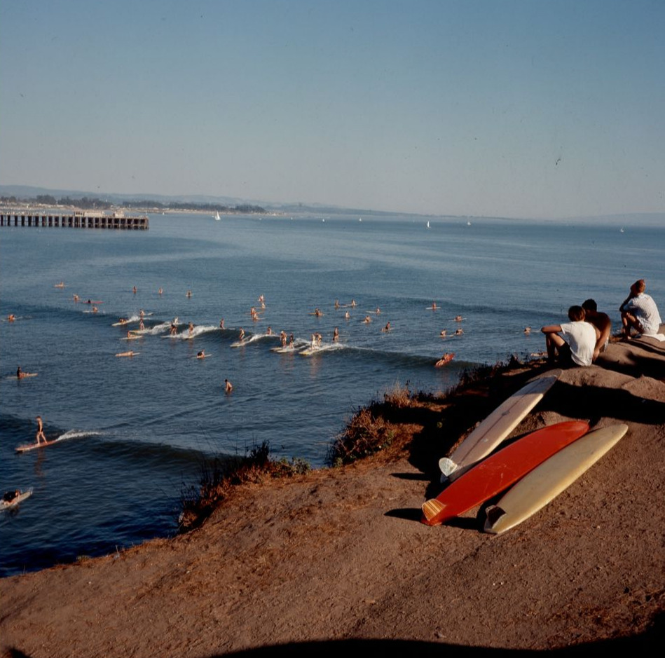 Surfers sitting on a cliff above the ocean. 