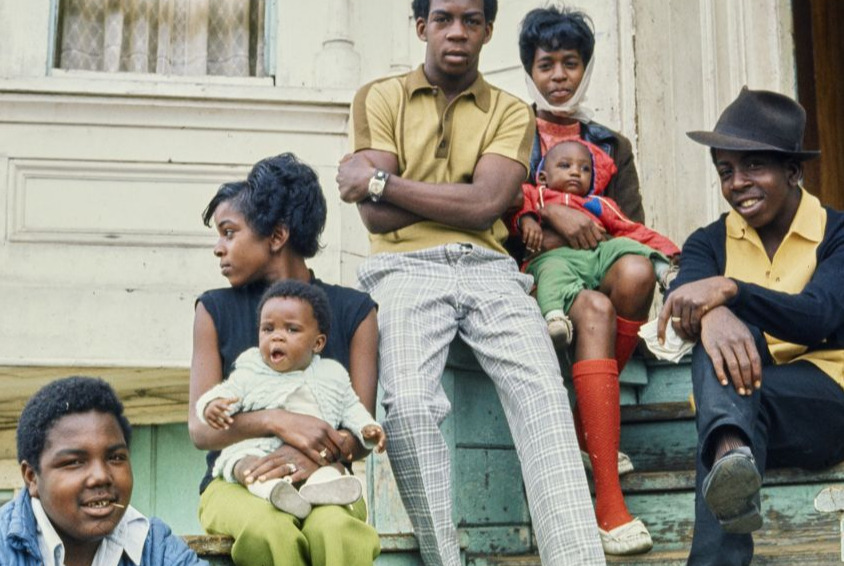 Group of African American men and women sitting on a porch stoop.